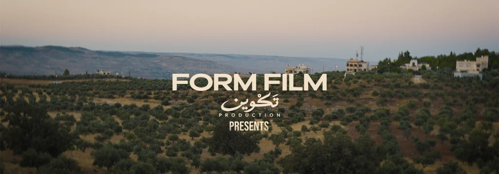 Opening production credits over olive groves and hillside buildings at dusk.